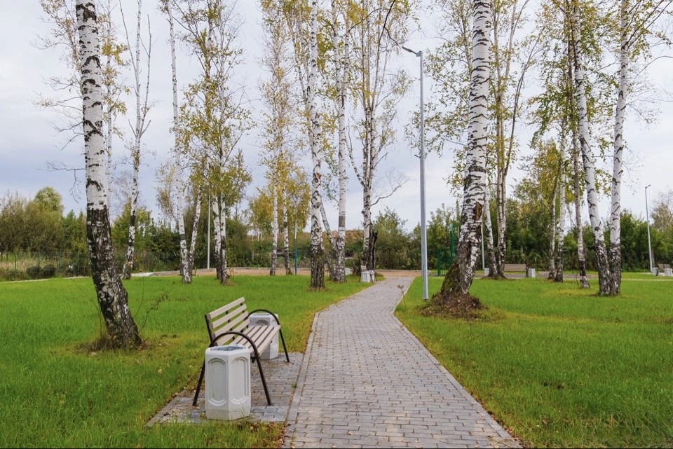 Modern two-story house at dusk, with large windows and warm interior lighting. A car is parked in the driveway; the sky is cloudy, creating a cozy atmosphere.